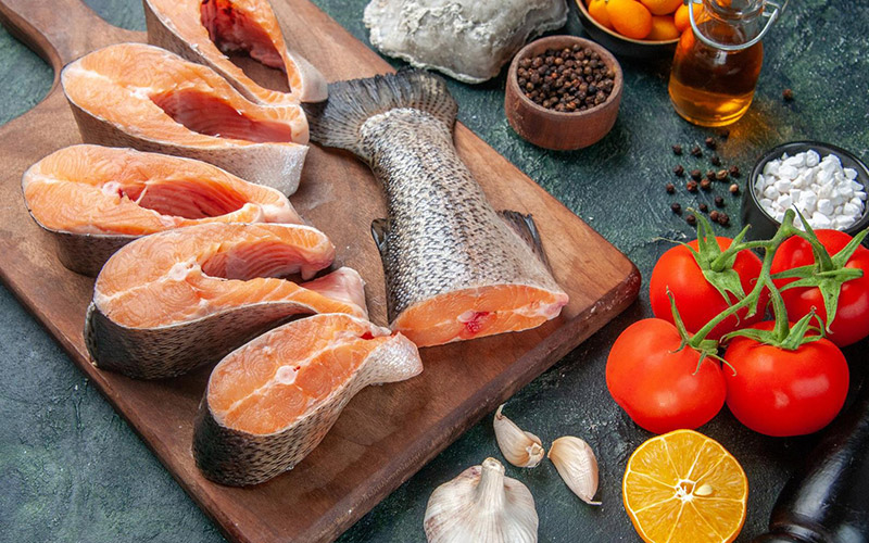 Raw-Salmon-filets-on-chopping-board-with-fish-tail-and-condiments