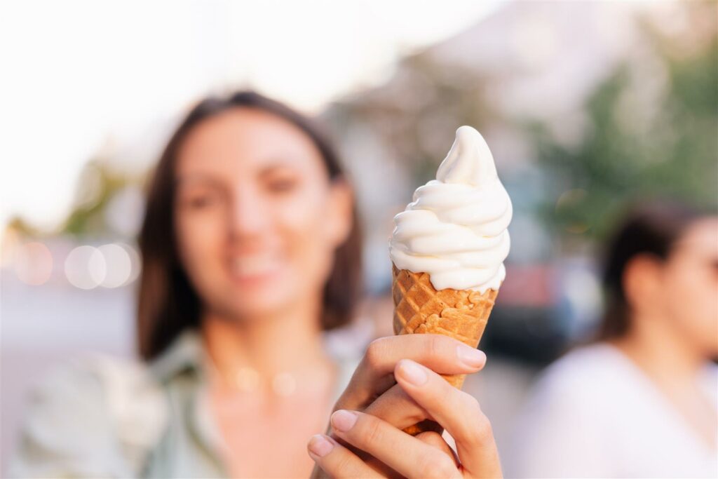 Woman outdoor  at summer sunset time having ice cream cone positive happy playful at city street